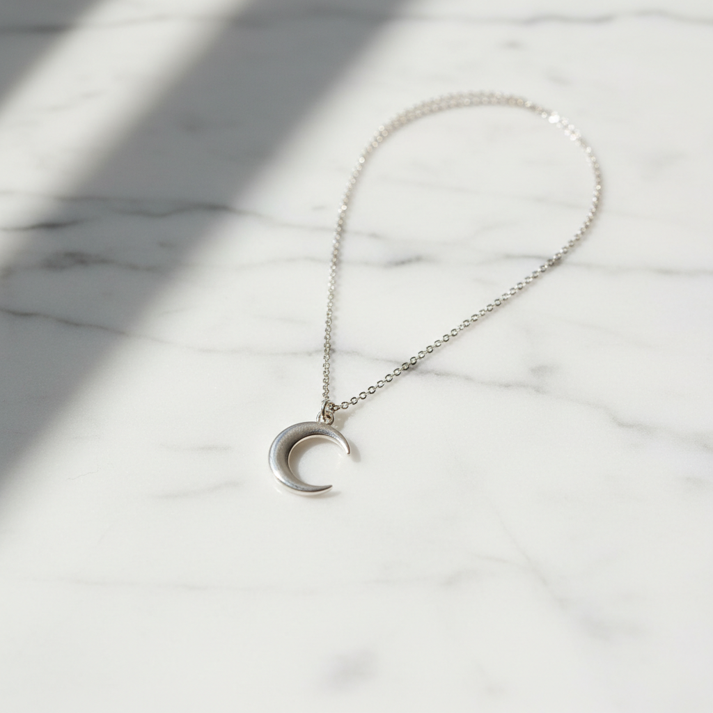 Dainty sterling silver crescent moon pendant necklace on white marble